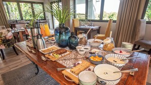 Un buffet per la colazione con diversi cibi e bevande, una macchina del caffè e un vaso con una pianta.