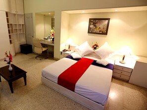 A hotel room with a bed, a desk, a chair, a wardrobe, and a painting on the wall.