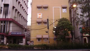A multi-story building with a yellow facade, several windows with awnings, and a sign for the Department of Posts, India Officers' Quarter. - Innra (Kolkata)
