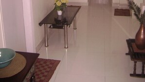 A hallway with a dining table, chairs, a vase with flowers, a fire extinguisher, and a door. - Innra (Kolkata)