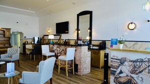A hotel lobby with a reception desk, seating area, and a large mirror. - Hotel Poveira (Porto)