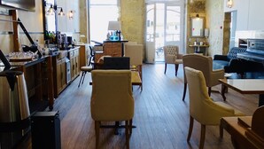 A spacious living area with wooden flooring, a bar area with a TV, and a piano. - Hotel Poveira (Porto)