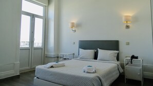 A hotel room with a bed, two bedside lamps, a nightstand, and a window. - Hotel Poveira (Porto)
