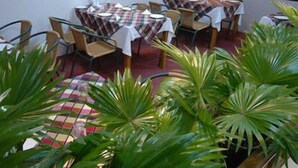 A dining area with round tables covered with checkered tablecloths, surrounded by chairs. - Rose wood Residence (Dhaka)