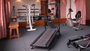 A gym with exercise equipment, a mirror, and pink curtains. - Rose wood Residence (Dhaka)