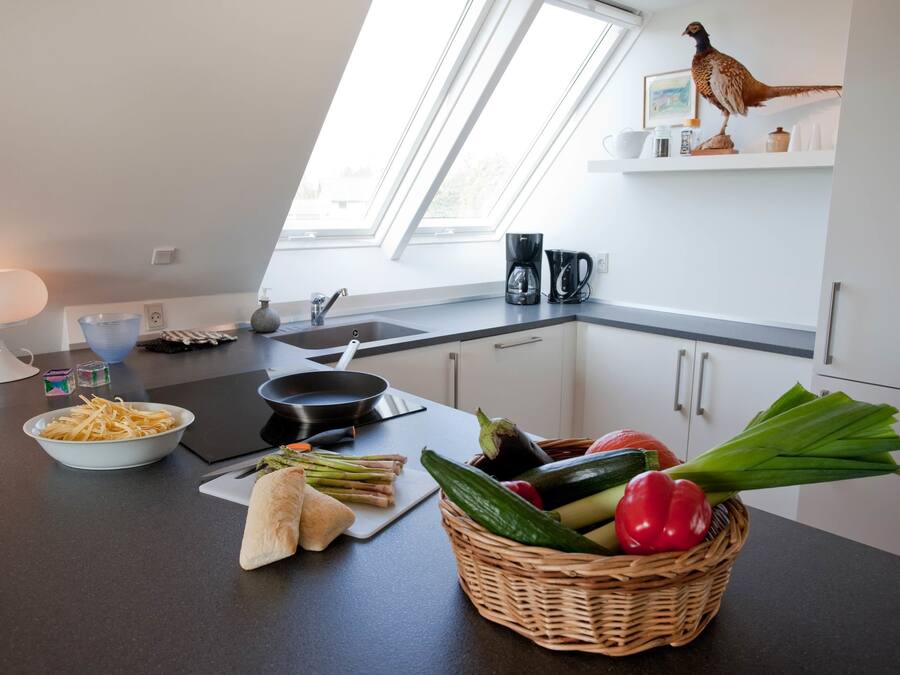 Una cocina moderna con tragaluz, cafetera y verduras frescas en la encimera.
