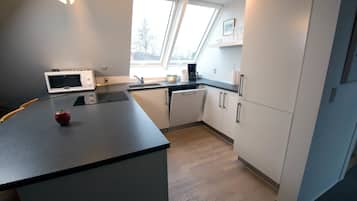 A modern kitchen with a microwave, coffee maker, and a small fruit bowl on the counter.