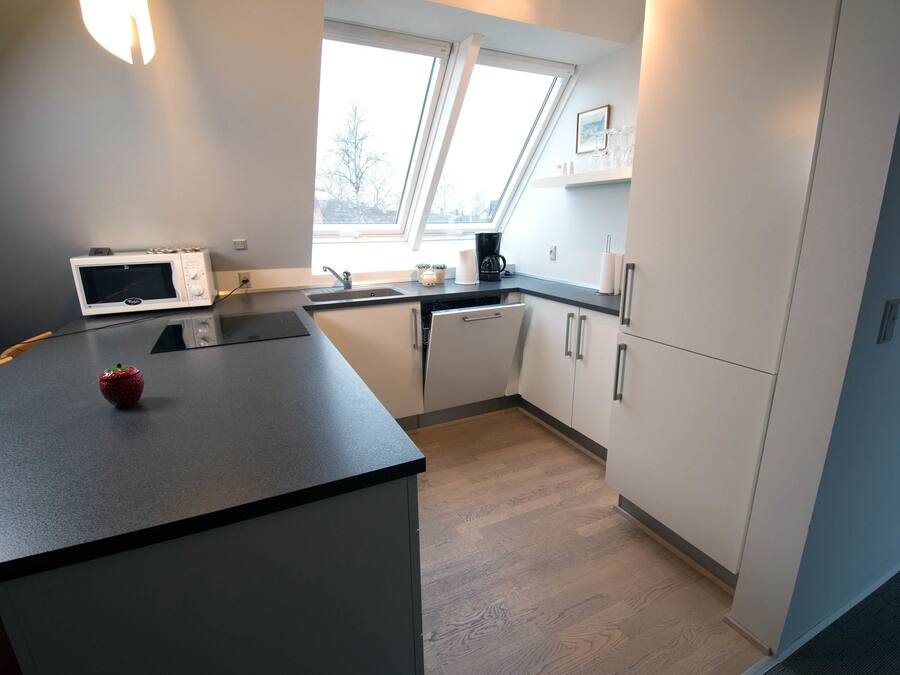 A modern kitchen with a microwave, coffee maker, and a small fruit bowl on the counter.