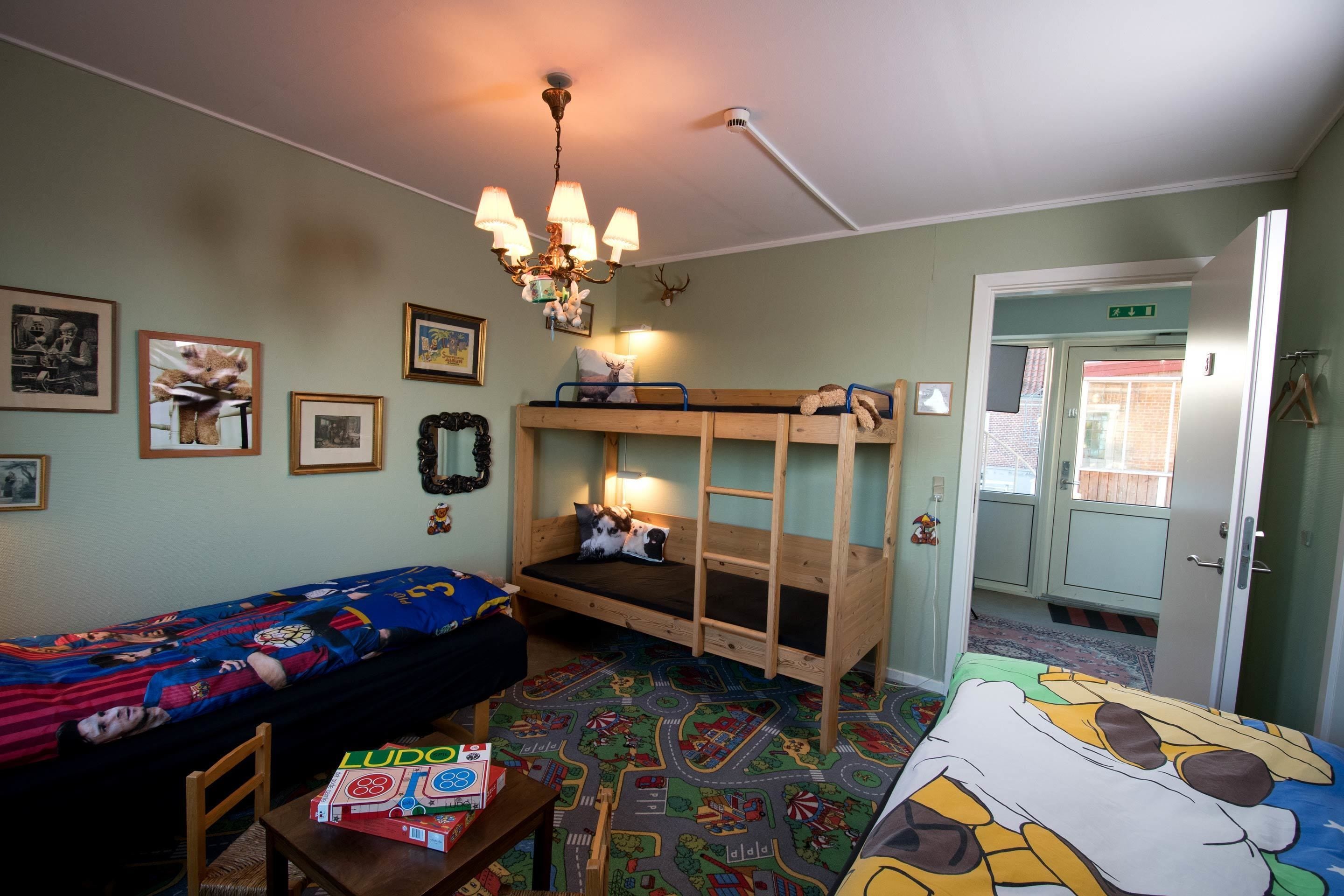 A room with bunk beds, a table with a board game, and a chandelier.