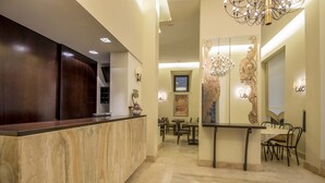 A hotel reception area with a marble reception desk, a dining area with chairs and tables, and a chandelier. - Albergo Sant'Emidio (Ascoli Piceno)