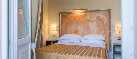 A hotel room with a bed, two bedside tables, a nightstand, and a large painting on the wall.