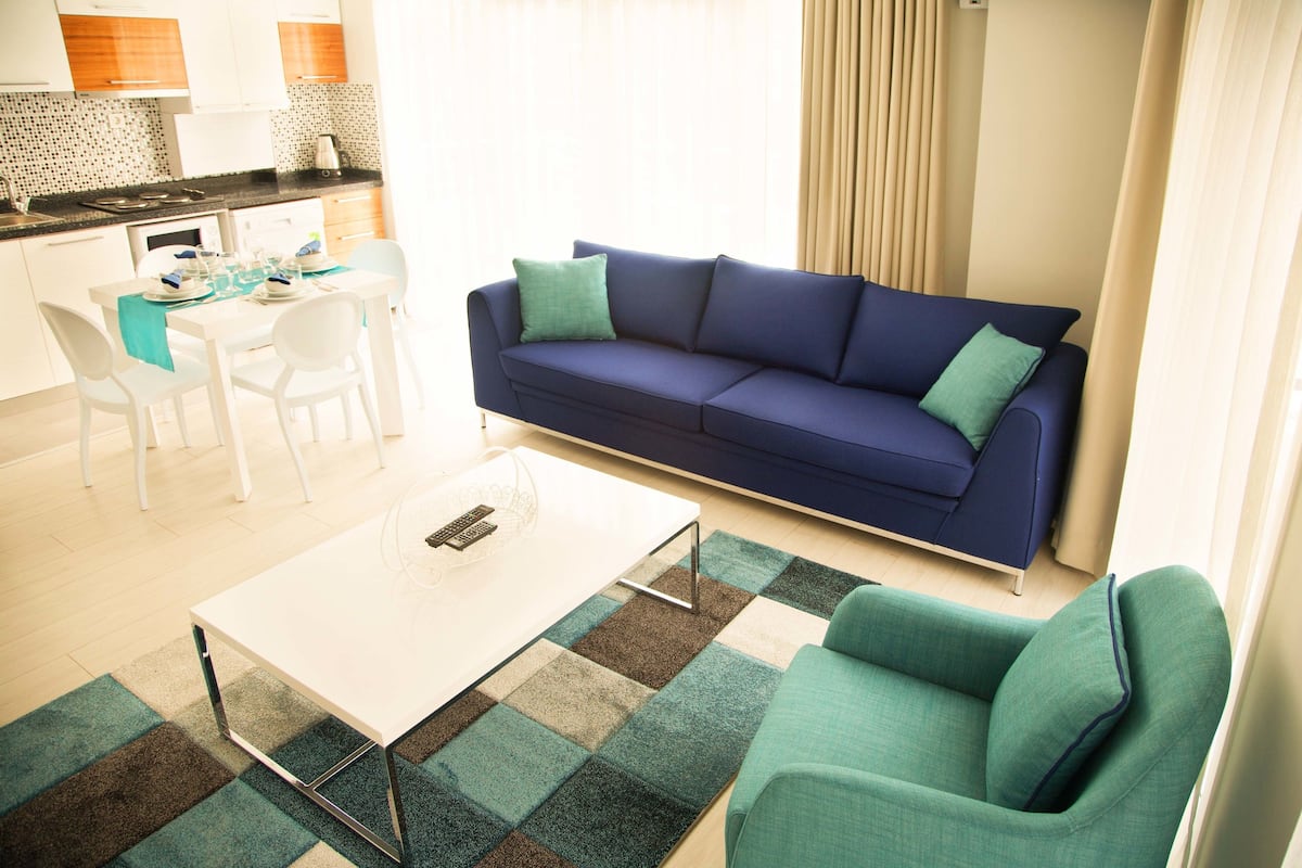 Un salon moderne avec un canapé bleu, une table basse blanche et un tapis à carreaux.