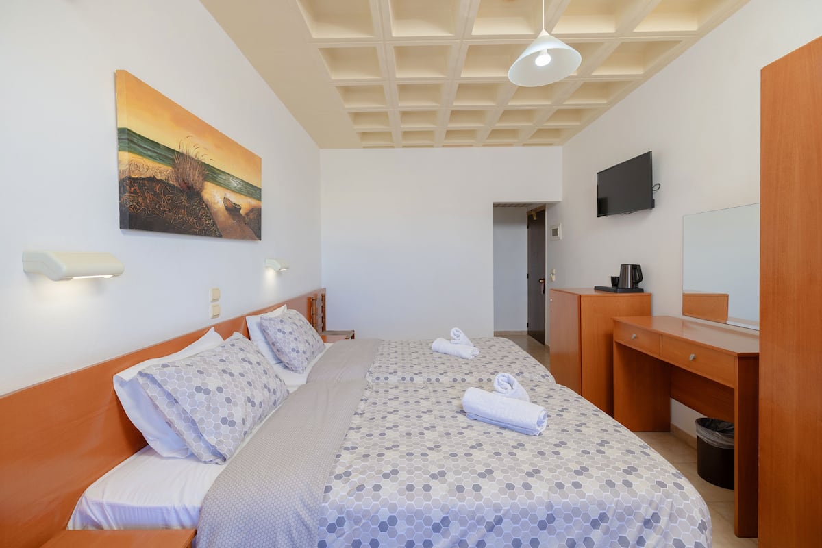 Ein Hotelzimmer mit einem Bett, einem Schreibtisch, einem Fernseher und einem Bild an der Wand.