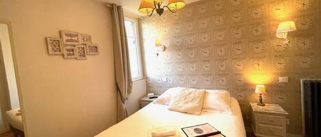 A hotel room with a bed, bedside lamps, a clock wallpaper, and a chandelier.
