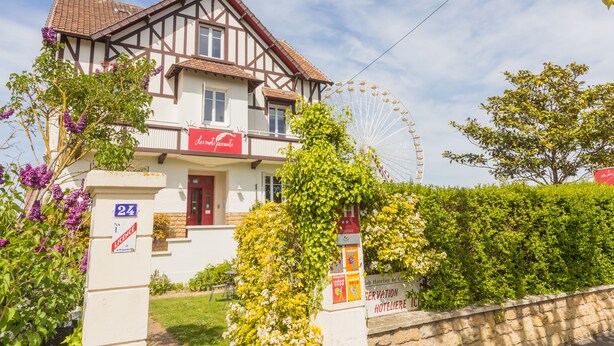 Un edificio tradicional con entramado de madera, una puerta roja y un letrero que dice 'Hotel de France'.