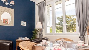 Un comedor con una mesa lista para cuatro personas, un espejo y una lámpara en la pared.