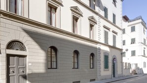 A multi-story building with a symmetrical facade, large windows, and a prominent entrance with a door and a small balcony. - Palazzo Branchi (Florence)