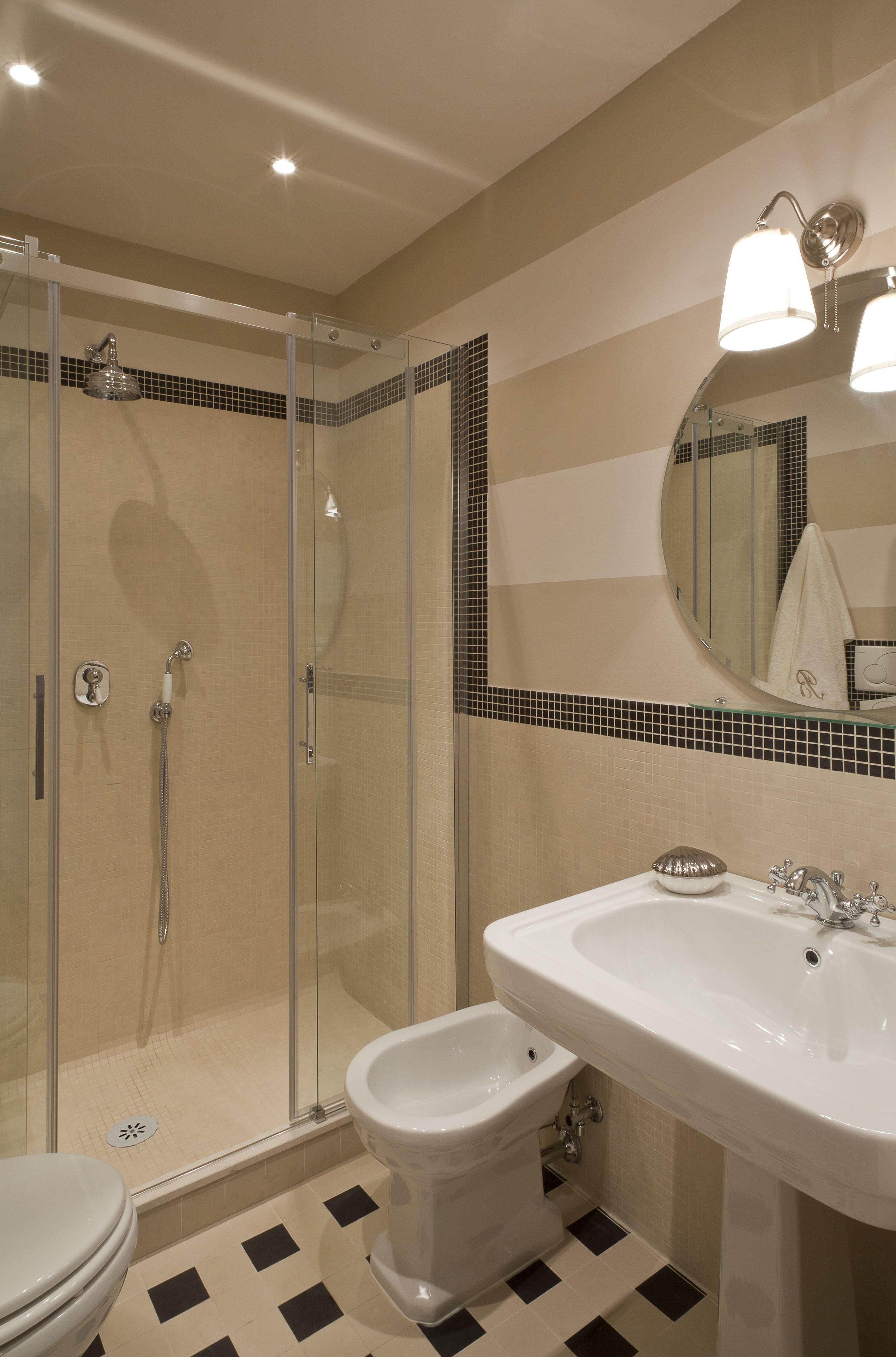 A bathroom with a glass-enclosed shower, a bidet, and a sink with a mirror above.