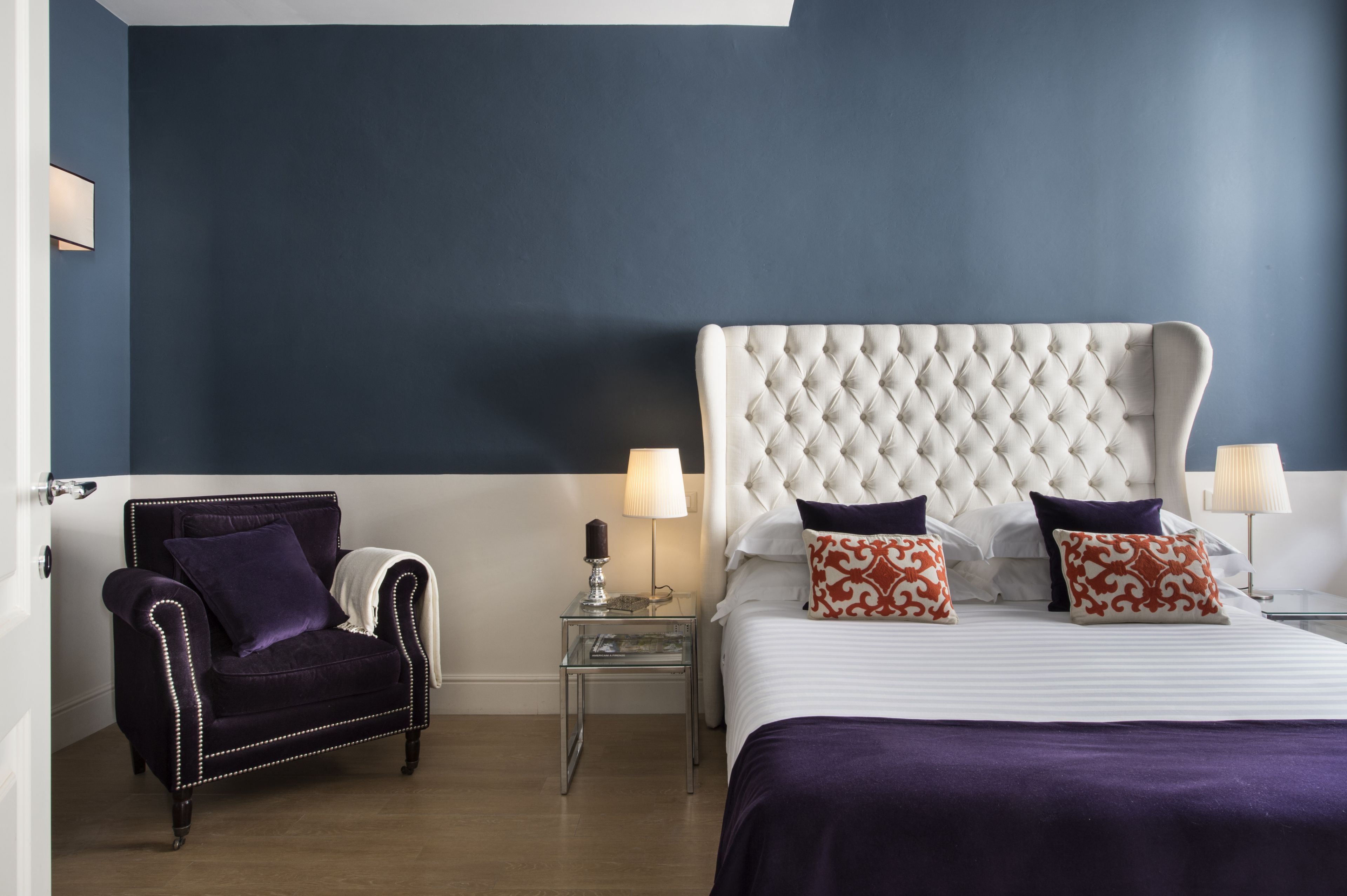 A hotel room with a large bed, a chair, a nightstand, and a lamp.