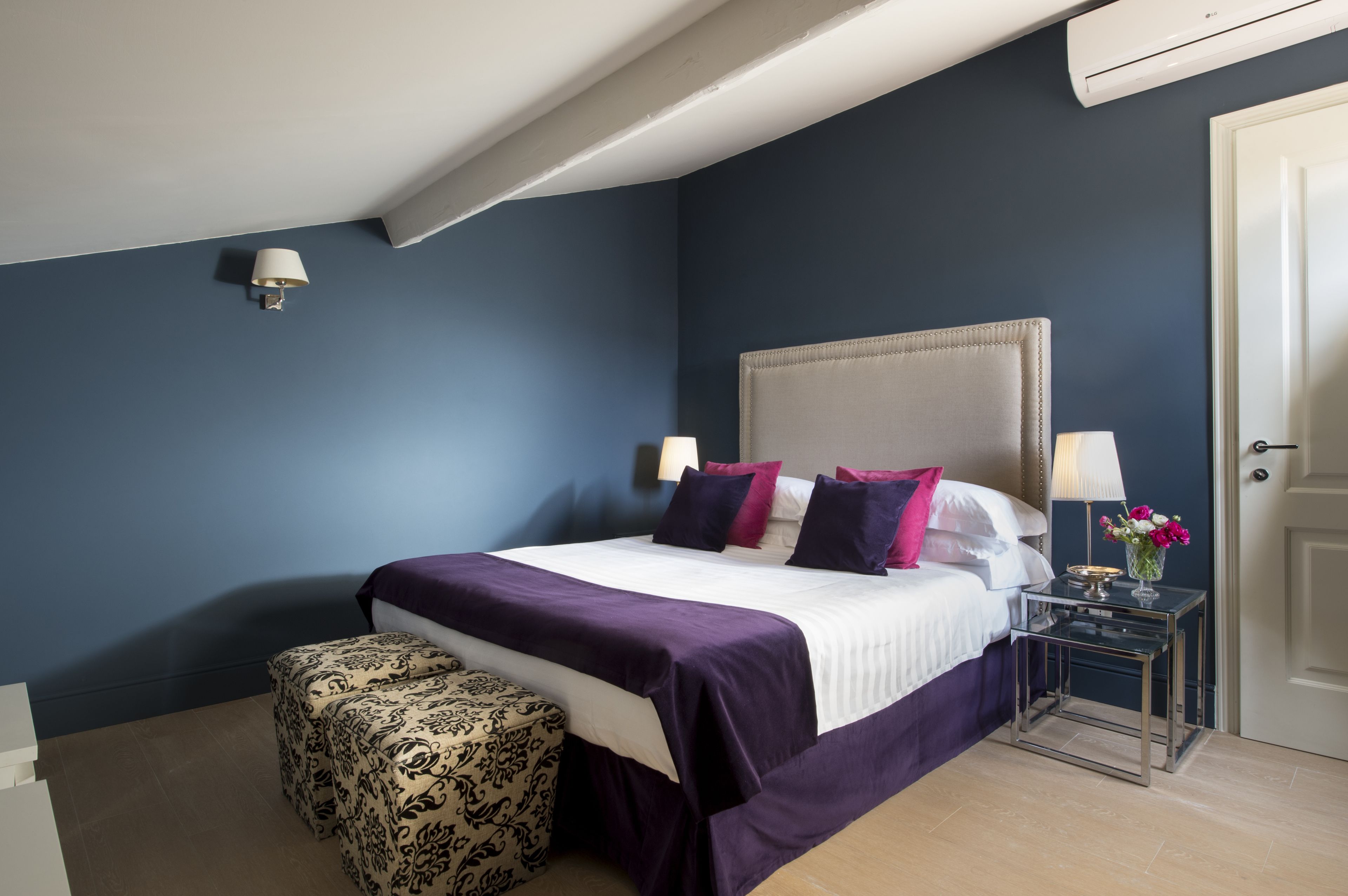 A bedroom with a large bed, a bedside table with a lamp, and a decorative vase.