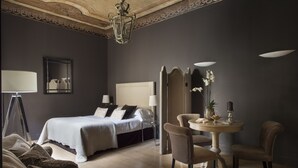 A hotel room with a bed, bedside lamps, a round table with chairs, and a mirror on the wall. - Palazzo Branchi (Florence)