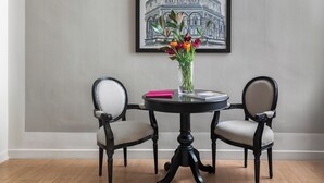 A round table with two chairs, a vase with flowers, and a framed picture on the wall. - Palazzo Branchi (Florence)