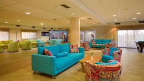 A spacious lobby with a large blue sofa, patterned armchairs, and a pool table. - Solimar Ruby (Hersonissos)