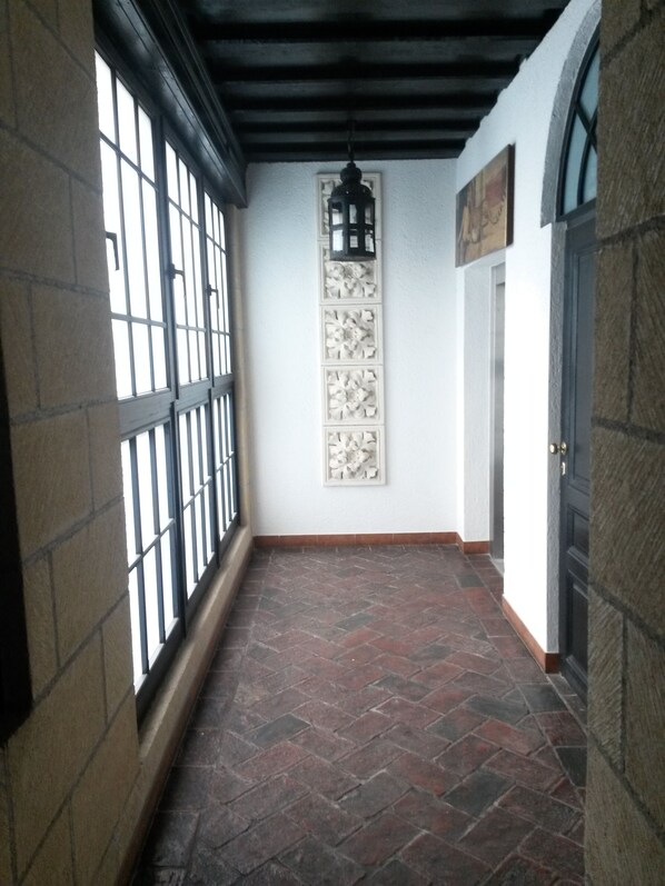 A corridor with a tiled floor, a black door, and a wall-mounted decorative panel.