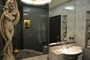 A modern bathroom with a marble sink, a large mirror, a bathtub, and a statue. - Citadella Residence Appartments Vienna (Vienna)