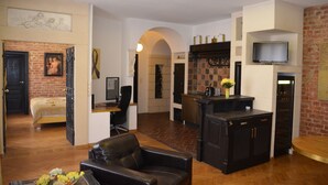 A spacious living area with a fireplace, a television mounted on the wall, and a dining area with a kitchen counter. - Citadella Residence Appartments Vienna (Vienna)