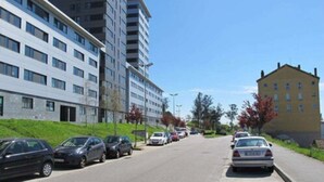 A street lined with parked cars and modern apartment buildings.