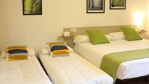 A hotel room with two single beds, a nightstand, and a lamp.