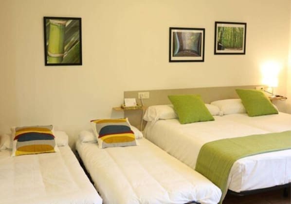 Una habitación de hotel con dos camas individuales, una mesita de noche y una lámpara.