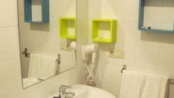 Une salle de bain avec un lavabo blanc, un miroir et deux porte-serviettes.