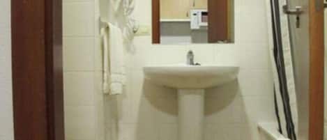 Un baño pequeño con lavamanos, espejo e inodoro con ducha.