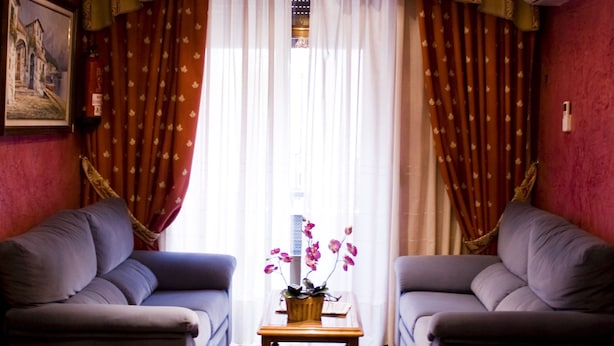 A room with two sofas, a chandelier, a table with flowers, and a painting on the wall.
