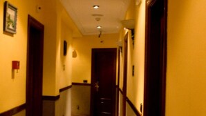 A hotel hallway with a marble-patterned carpet, wooden doors, and recessed lighting.