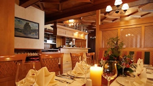 A dining area with a table set for four, featuring a candle centerpiece, wine glasses, and neatly folded napkins. - Hotel Zum Kanzler (Südharz)