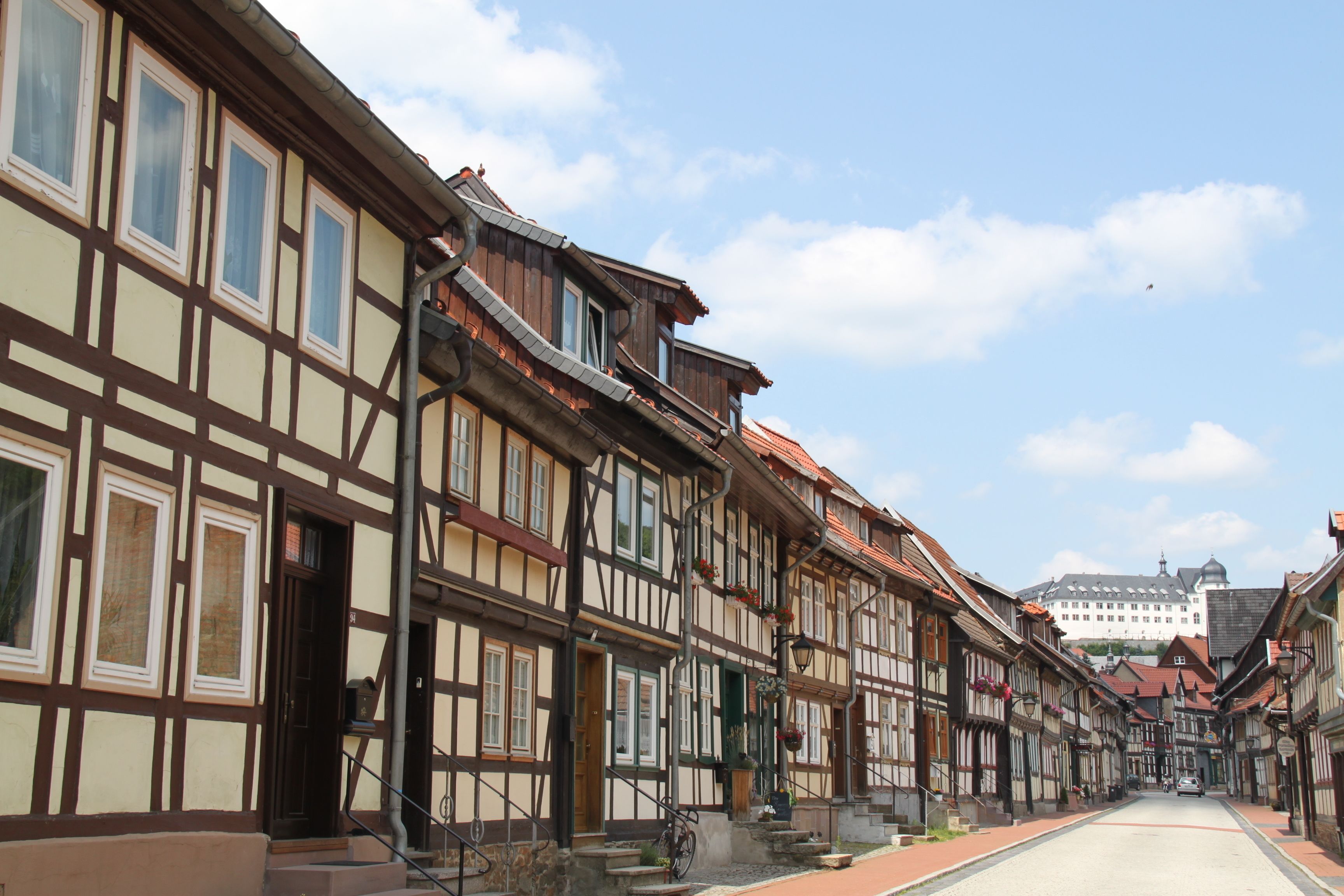 Un bâtiment traditionnel à colombages, doté d’une cour intérieure et surmonté d’un bâtiment blanc en arrière-plan.