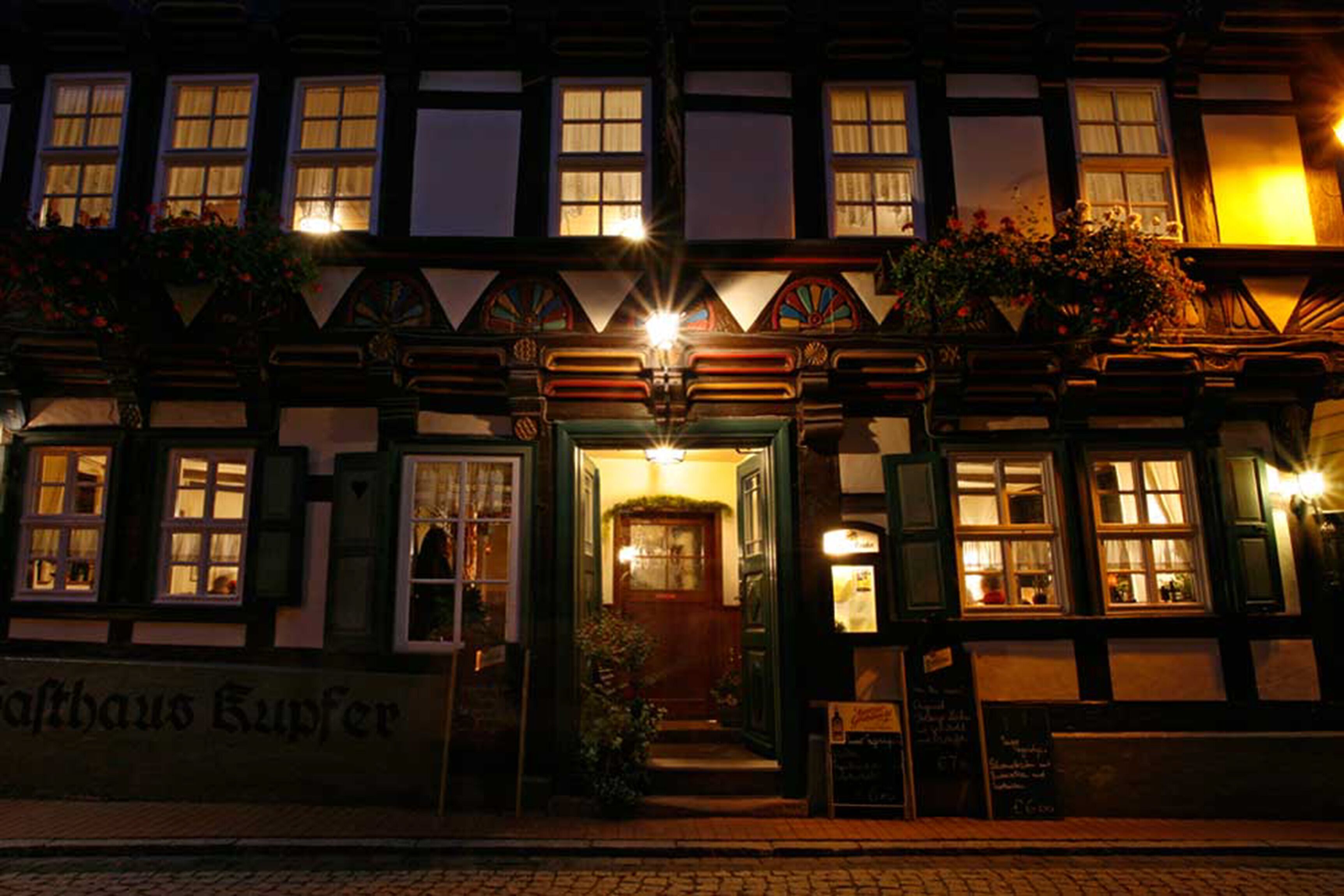 En traditionell europeisk byggnad med en mörk fasad, flera fönster och en skylt med texten ”Saffhaus Kupfer”.