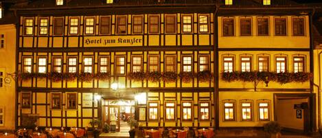 A traditional European hotel with multiple floors, a sign reading "Hotel zum Ranzler," and outdoor seating with tables and chairs.