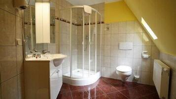 A bathroom with a shower enclosure, a toilet, and a sink.