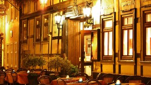An outdoor dining area with tables set for two, covered with red tablecloths, and surrounded by wooden chairs. - Hotel Zum Kanzler (Südharz)