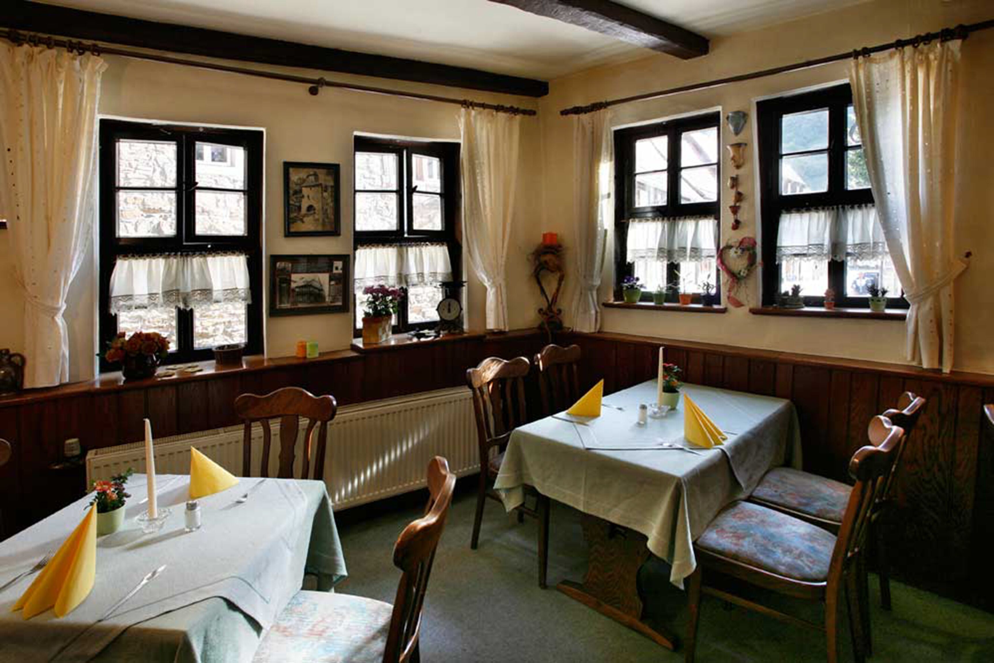 A cozy dining area with wooden furniture and large windows.