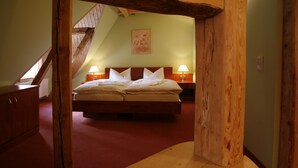 A bedroom with a wooden headboard, a bed with white linens, two bedside lamps, and a wooden staircase in the background. - Hotel Zum Kanzler (Südharz)
