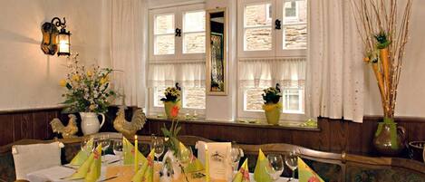 A dining area with a table set for four, featuring yellow napkins, a candle, and a vase with flowers.