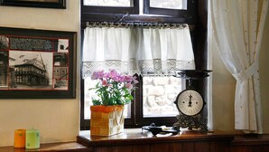A window with a white curtain, a clock, a potted plant, and a framed picture on the wall. - Hotel Zum Kanzler (Südharz)
