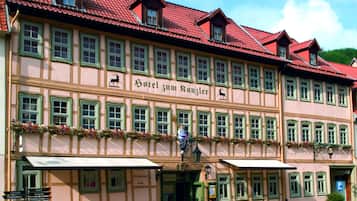 Traditional half-timbered building with a red-tiled roof and charming facade featuring a row of windows with green shutters.
