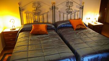 A double bed with a metal headboard, two bedside tables with lamps, and a blue quilted bedspread.