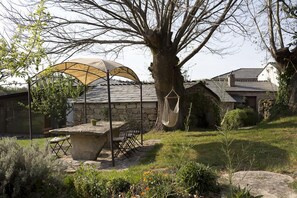 Un patio de piedra con mesa y sillas, una silla colgante y una pérgola con dosel.